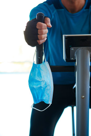closeup of a young caucasian man in the gym, wearing sportswear, using a stationary bike, and his...