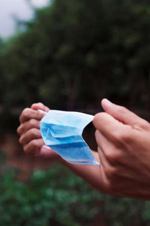 closeup of a young farmer man about to put on a surgical mask in an organic orchardの写真素材