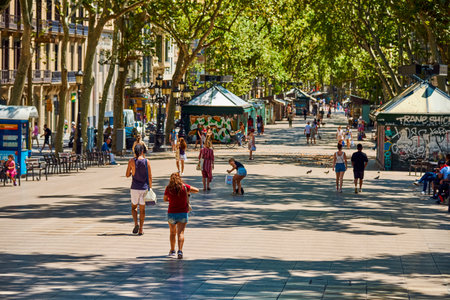 BARCELONA, SPAIN - AUGUST 7, 2020: Few people walking by the popular Las Ramblas in Barcelona,...