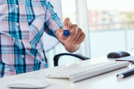closeup of a young caucasian man sitting at his office desk disinfecting his computer keyboard by...