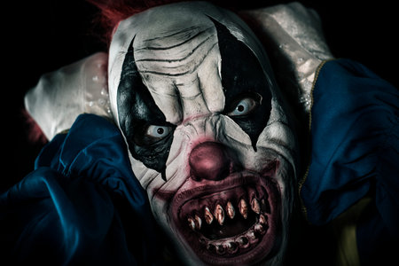 closeup of a scary evil clown with frightening white eyes and bloody teeth, pulling his red hair...