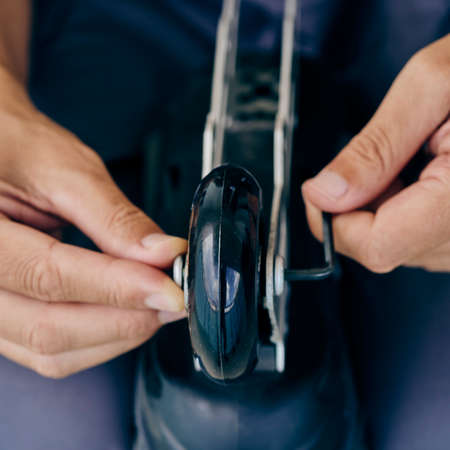 high angle view of a caucasian man changing the wheels of an inline skate, using an hex keyの写真素材