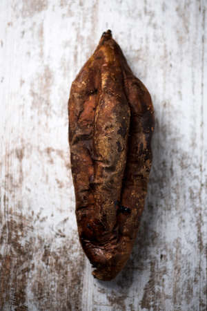 high angle view of a roasted sweet potato on a rustic white wooden surfaceの写真素材