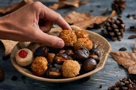 closeup of a man taking a panellet, a typical confection of Catalonia, Spain, eaten traditionally in...