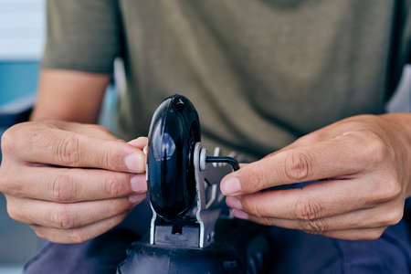 closeup of a caucasian man changing the wheels of an inline skate, using a hex keyの写真素材