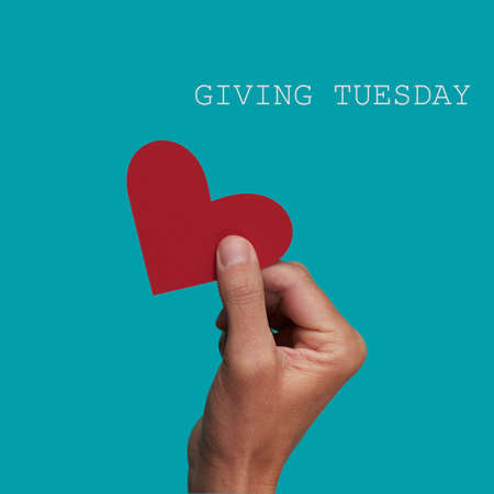 a person giving a red heart to another person and the text giving tuesday on a blue backgroundの写真素材