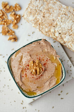high angle view of a bowl with an appetizing hummus, made with chickpea, walnut and rosemary, on a...