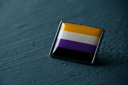 closeup of a non-binary pride flag in a pin button on a dark gray surfaceの写真素材