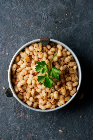 high angle view of some fried white beans served in an old metallic lunch box, on a slate stone...
