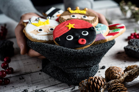closeup of a young caucasian man with knitted bag in his hand with a pile of christmas cookies with...