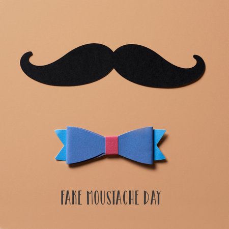 closeup of a moustache, made with a cutout of a black cardboard, a bow tie and the text fake moustache day on a brown background, in square formatの写真素材