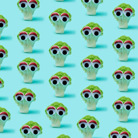 some broccoli heads with funny googly eyes, standing on a blue background, forming a mosaic, in a square formatの写真素材