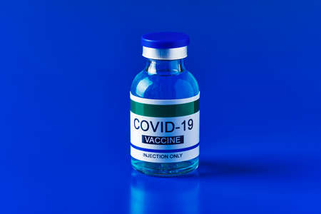 a simulated covid-19 vaccine bottle on a blue background, with some blank space around itの写真素材