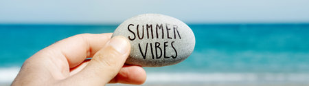 closeup of a caucasian man on the beach holding a stone, with the text summer vibes written in it,...
