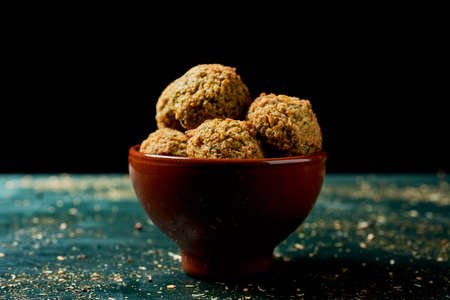 closeup of an earthenware bowl with some falafel on a rustic green wooden tableの写真素材