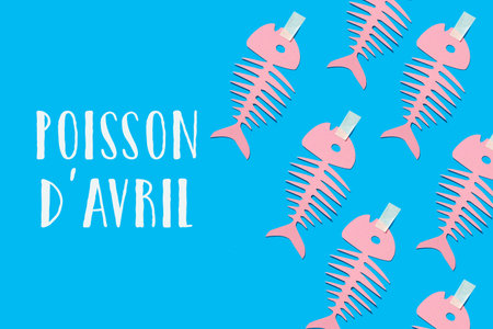 some homemade pink paper fishes and text fish of april written in french, the equivalent of april...