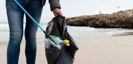 a man is collecting some waste, such as cans, bottles or bags, from the sand of a lonely beach, as...