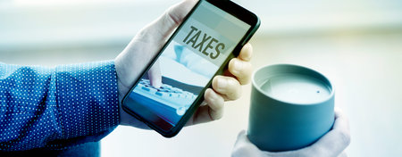 a young man, wearing a blue shirt, has his smartphone in one hand, with the text taxes in its...
