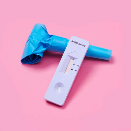 a covid-19 antigen diagnostic test device and a blue party horn on a pink background, as a safe party setの写真素材