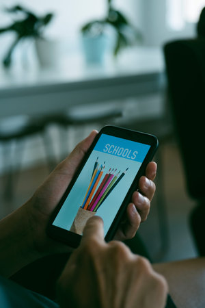 a young caucasian man searches schools online with his smartphone, with a simulated mock engine in...
