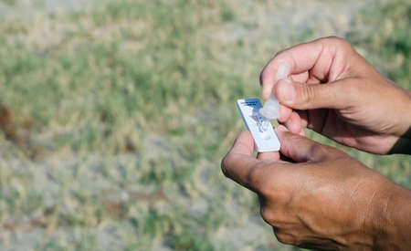 closeup of a young caucasian man outdoors placing his own sample into the covid-19 antigen diagnostic test deviceの写真素材