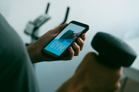 closeup of a young caucasian man lifting a dumbbell in the living room of his house while is looking...