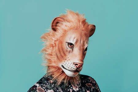 closeup of a young man wearing a lion mask on a blue background with some blank space around himの写真素材