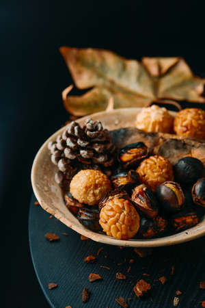 a plate with food traditionally eaten in All Saints Day in Catalonia, Spain, in a party called Castanada, such as roasted chestnuts, roasted sweet potato and panellets, a confection made with marzipanの写真素材