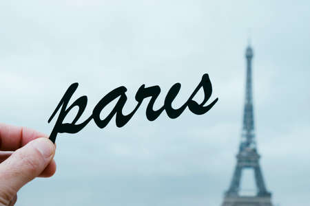 closeup of the hand of a young caucasian man holding the silhouette of the word Paris in front of he Eiffel Tower in Paris, Franceの写真素材