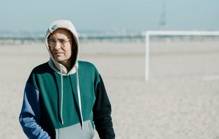 closeup of a mature man, wearing a multicolored hoodie and a pair of modern clear plastic-rimmed...