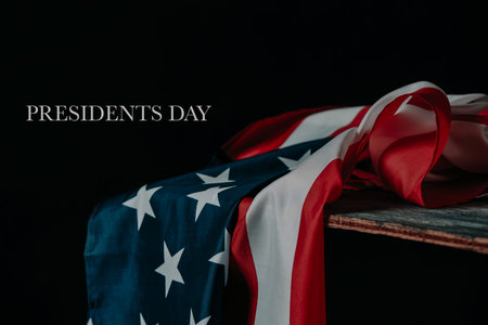 text presidents day and a flag of the united states of america lying on a rustic table, against a...