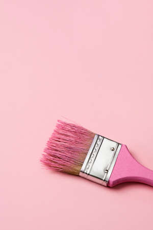 closeup of a pink paintbrush with some pink paint, on a pale pink background with some blank space on topの写真素材