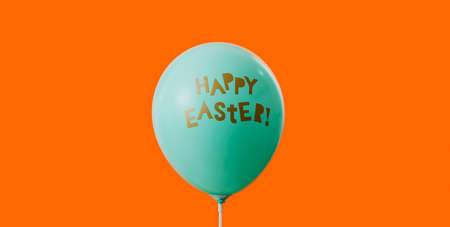 a blue balloon with the text happy easter written in it, on an orange backgroundの写真素材