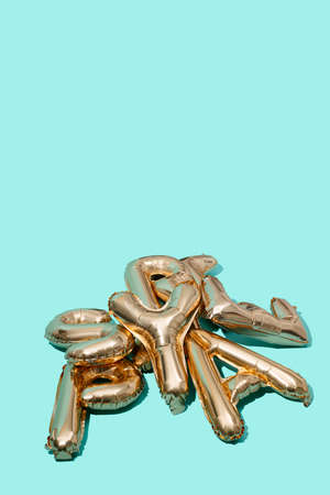 a pile of different golden letter-shaped balloons on a blue background with some blank space on topの写真素材