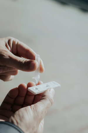closeup of a young man placing his own sample from a pipette into the covid-19 antigen diagnostic...