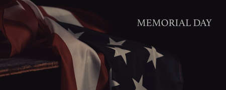 the text memorial day and the american flag laying on a surface, with a dramatic lighting, against a black background, in a panoramic format to use as web banner or headerの写真素材