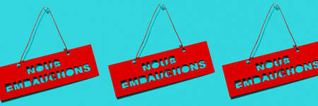 some red signs with the text we are hiring written in french hanging from a blue background, in a panoramic format to use as web banner or headerの写真素材