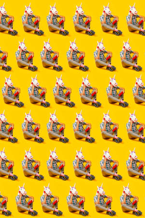 a mosaic of some men wearing unicorn masks talking on the phone, using colorful red landline telephones, arranged in different lines sitting on a yellow backgroundの写真素材