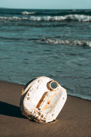 a piece of a used white plastic bottle on the wet sand of a beach, brought back to the seashore by the oceanの写真素材
