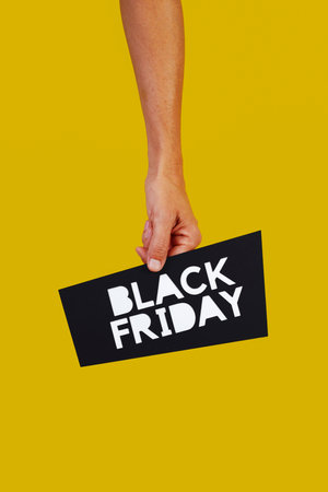 a man is holding a black sign in his hand with the text black friday, on a yellow backgroundの写真素材