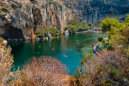 Vouliagmeni, Greece - September 1, 2022: Some people enjoy the good weather of a summer day on the Lake Vouliagmeni in Vouliagmeni, Greeceのeditorial素材