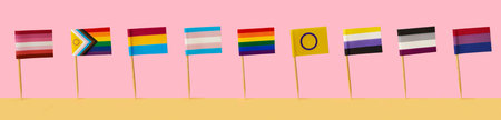 some different LGBTIQA flags attached to poles standing side by side on a yellow surface, against a...