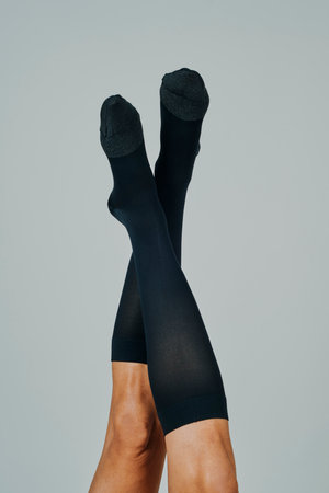 closeup of the legs of a man upside down wearing compression socks, on an off-white backgroundの写真素材