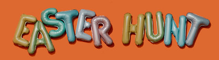 alphabet-shaped balloons of different colors forming the text easter hunt on an orange background, in a panoramic format to use as web banner or headerの写真素材