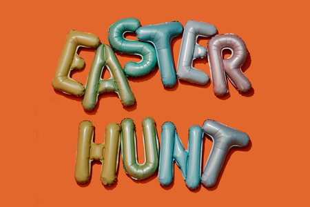 some alphabet-shaped balloons of different colors forming the text easter hunt on an orange backgroundの写真素材