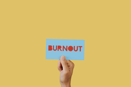 a man holds a blue sign with the text burnout on a yellow background with some blank space aroundの写真素材