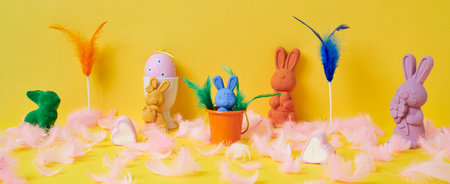 some easter bunnies of different colors, a pink easter egg in a white eggcup and some pink feathers ...