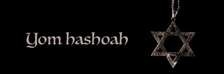 the text Yom Hashoah and an old and rusty pendant in the shape of the star of David on a black...