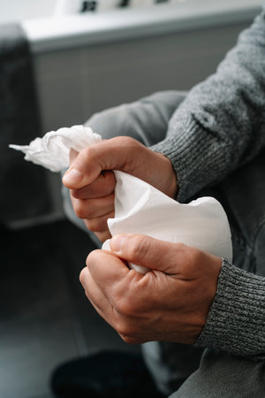 closeup of a caucasian man, sitting in the toilet, grabbing tight the toilet paperの写真素材