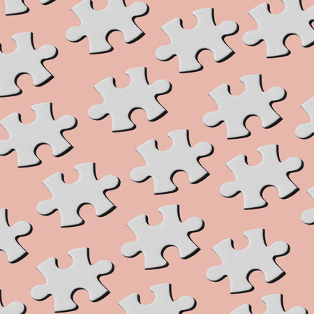 a pattern of white puzzle pieces arranged in different lines on a pale pink backgroundの写真素材